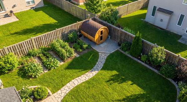 Aerial view of residential garden with barrel sauna properly positioned per regulations