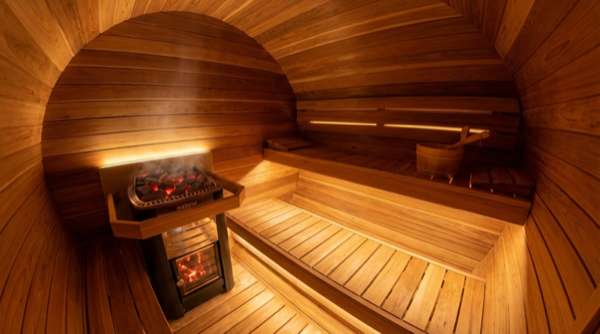 Innenansicht einer Premium-Fasssauna mit Zweistufenbänken und Saunaofen