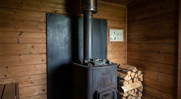 Fire protection plate behind wood-fired sauna heater